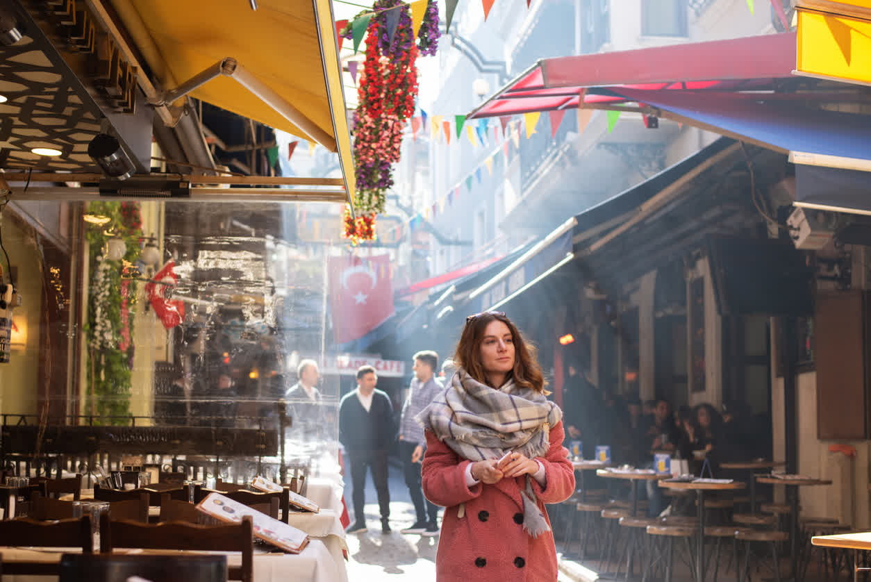 Traveler walking a lively Istanbul street lined with cafe terraces