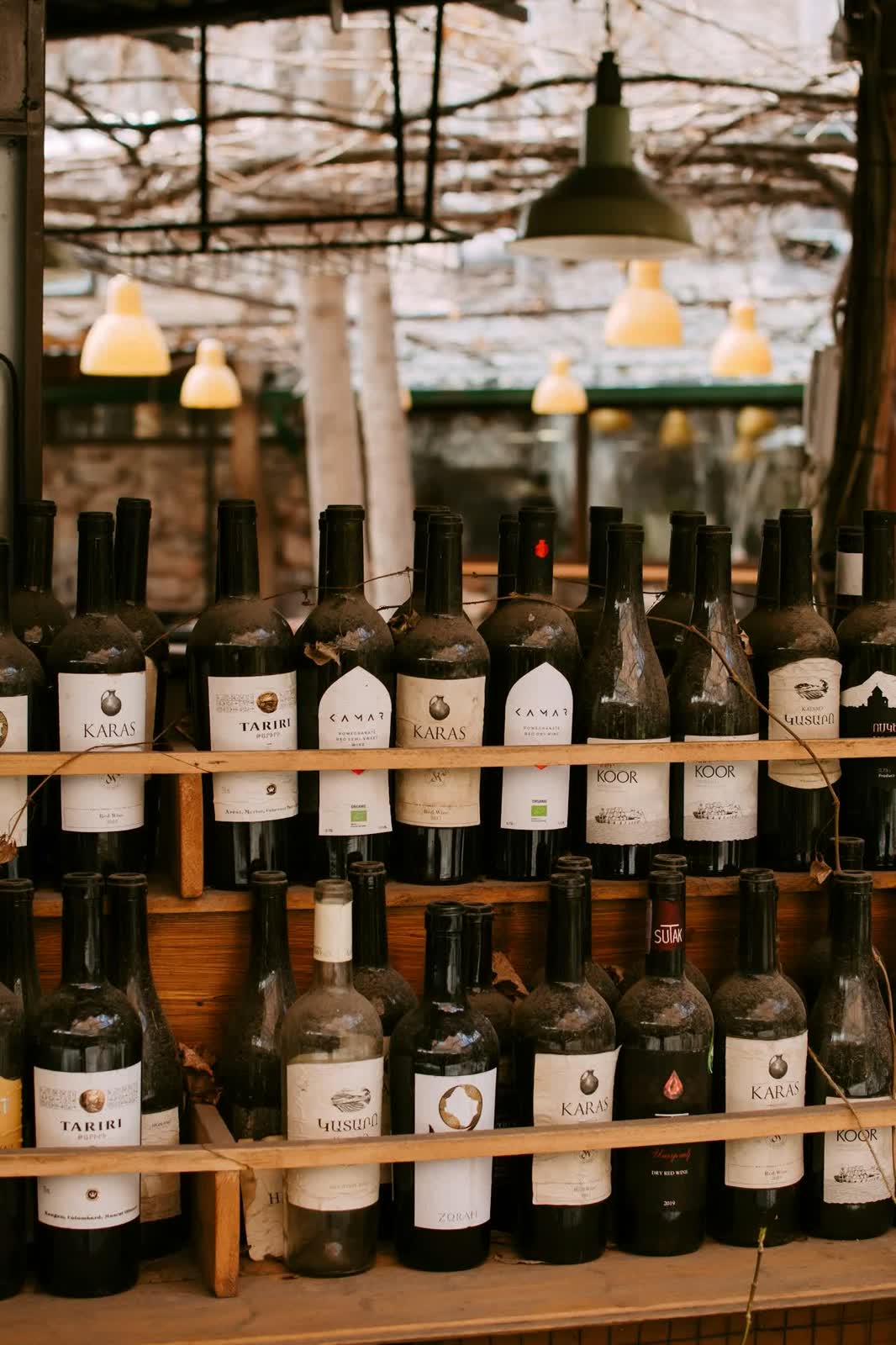 Shelves of wine bottles under the lamps of a restaurant terrace