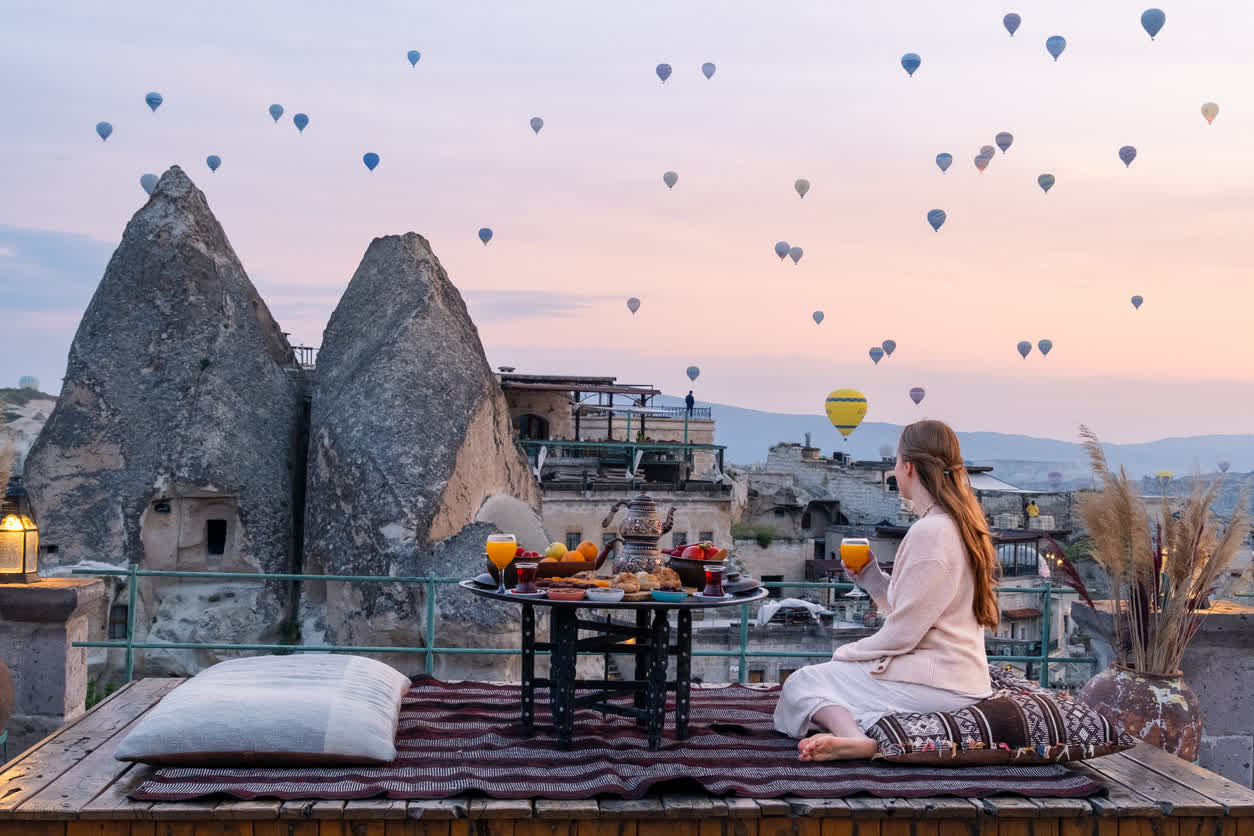 Rooftop breakfast at a Cappadocia cave hotel with hot air balloons overhead